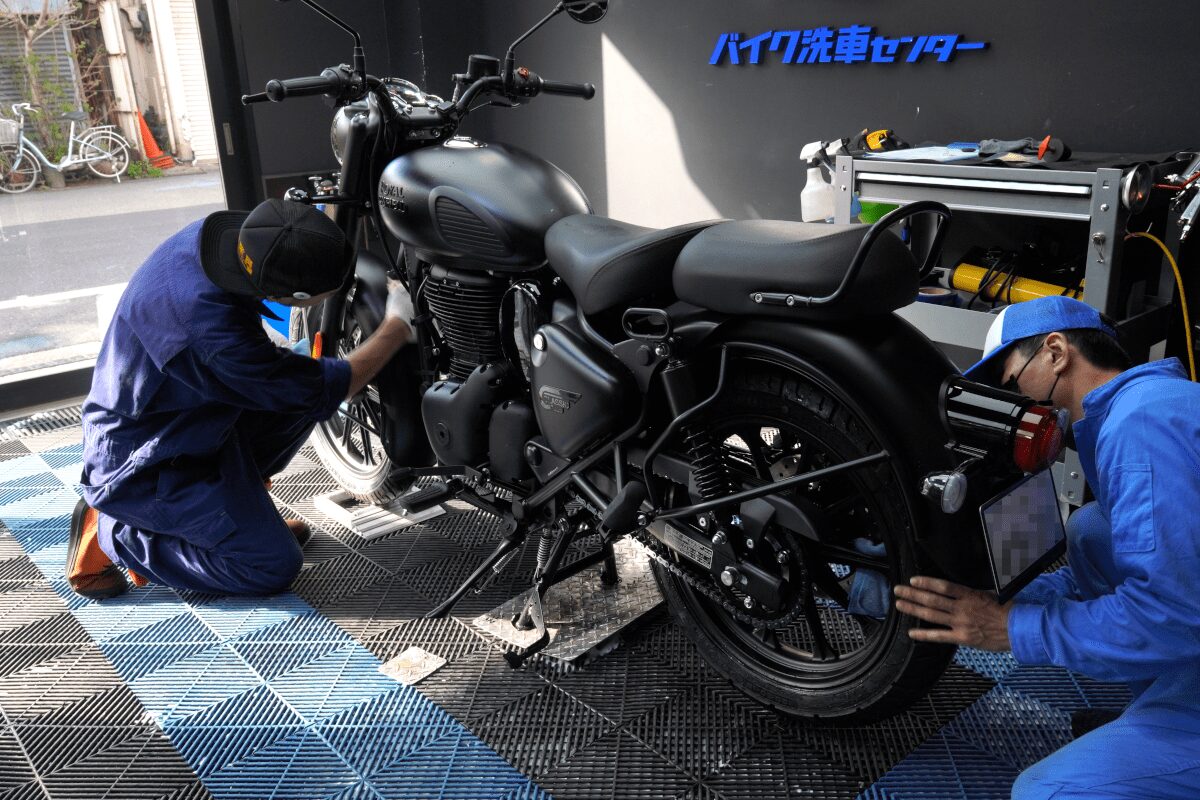 BB商会バイク洗車センターの洗車作業の様子　ROYAL ENFIELD CLASSIC350にガラスコーティング剤を塗布している状態　車体全体にコーティング剤を塗布