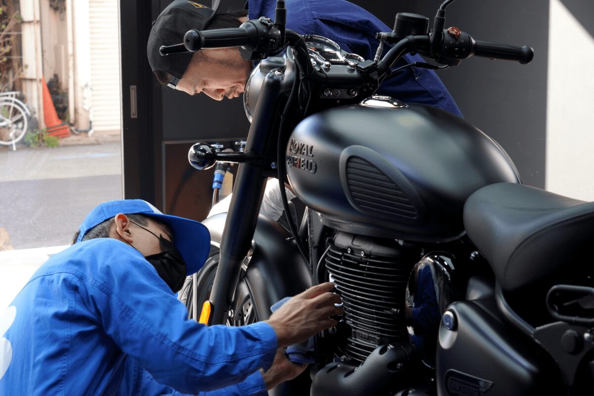 BB商会バイク洗車センターの洗車作業の様子　ROYAL ENFIELD CLASSIC350にガラスコーティング剤を塗布している状態　車体全体にコーティング剤を塗布