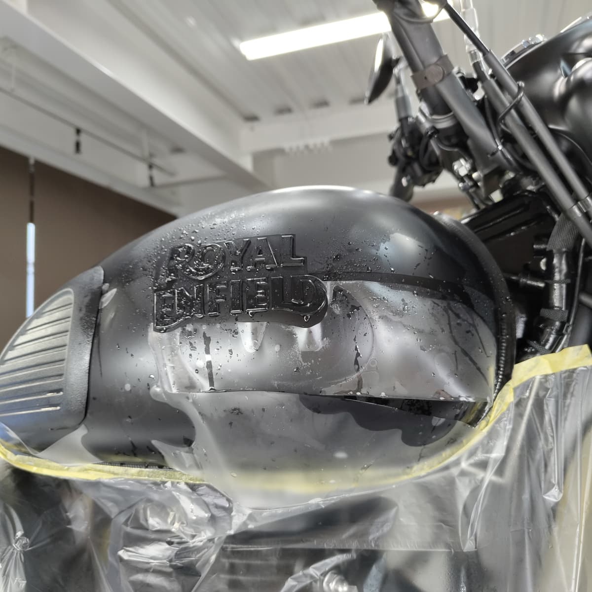 ROYAL ENFIELD CLASSIC 350のタンクにPPF施工（ペイントプロテクションフィルム施工）をしている様子　タンクの下部