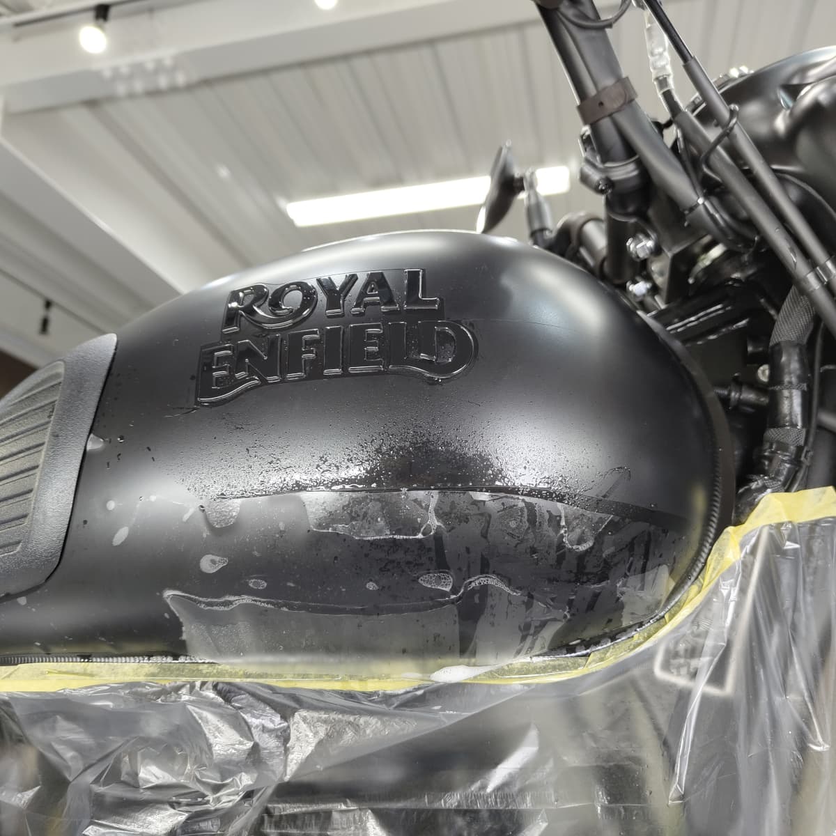 ROYAL ENFIELD CLASSIC 350のタンクにPPF施工（ペイントプロテクションフィルム施工）をしている様子　タンクの下部
